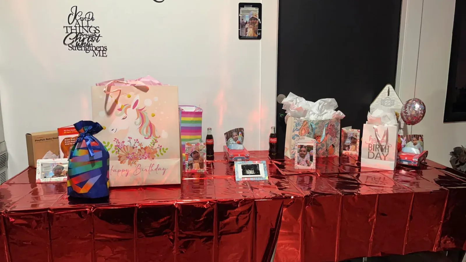 Birthday gift display with colorful bags, framed family photos, and metallic red linen