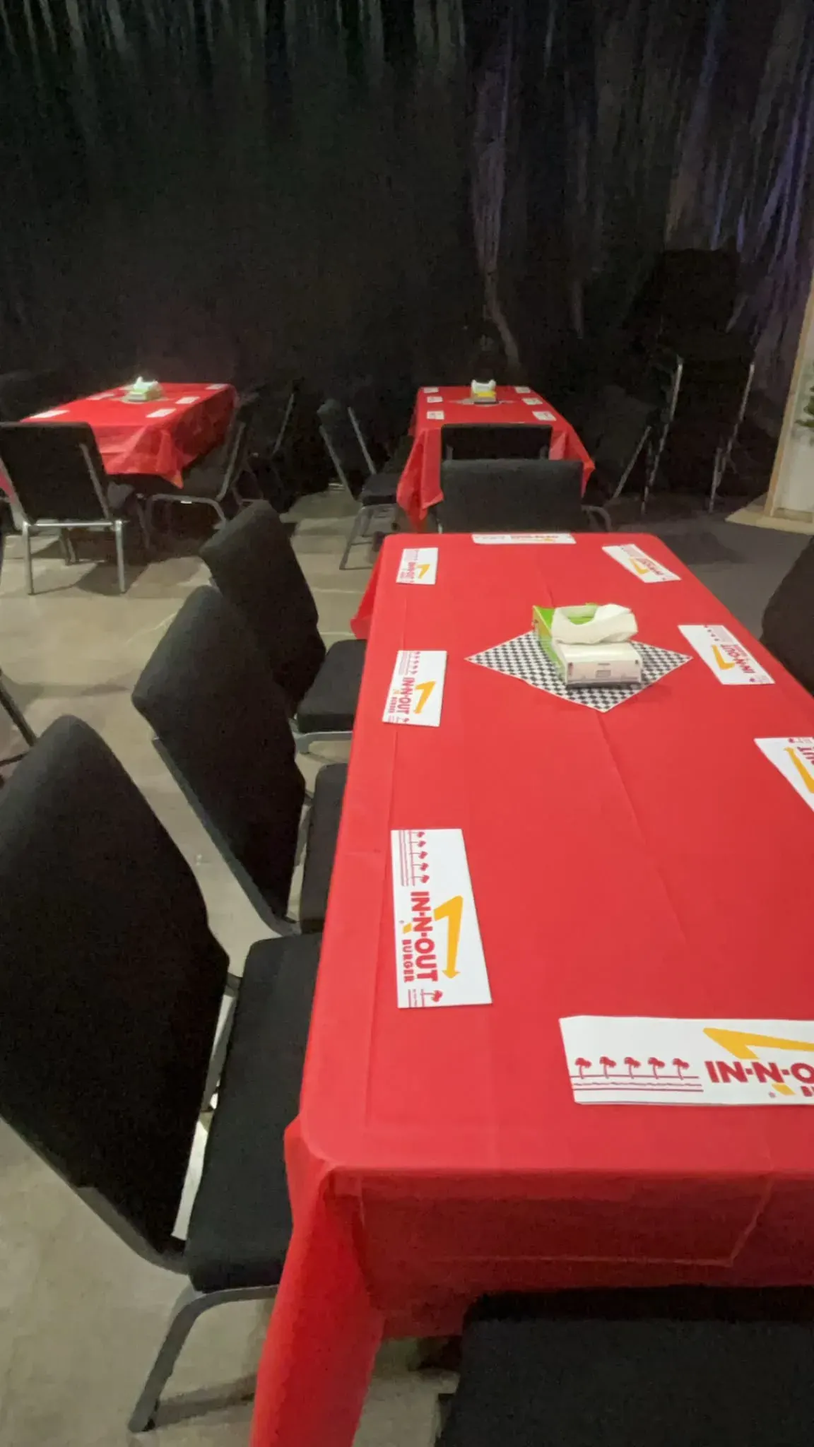 Guest tables with red linens, black chairs, and custom place settings