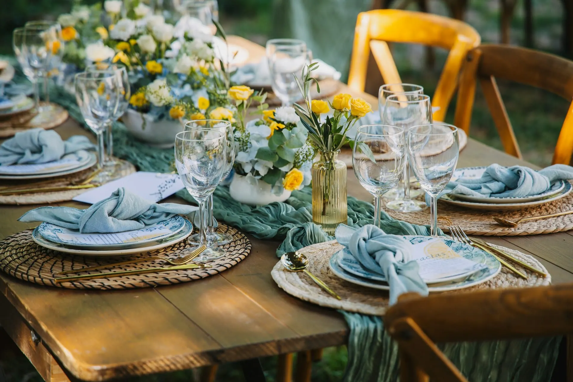 Layered outdoor event table with florals, linens, and glassware